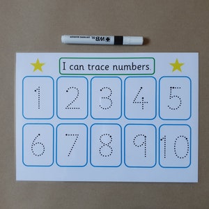 May include: A white educational worksheet with blue borders and the text "I can trace numbers." The numbers 1-10 are displayed in dotted lines for tracing. A white dry-erase marker is placed above the worksheet.
