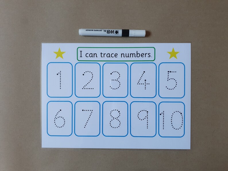 May include: A white educational worksheet with blue borders and the text "I can trace numbers." The numbers 1-10 are displayed in dotted lines for tracing. A white dry-erase marker is placed above the worksheet.
