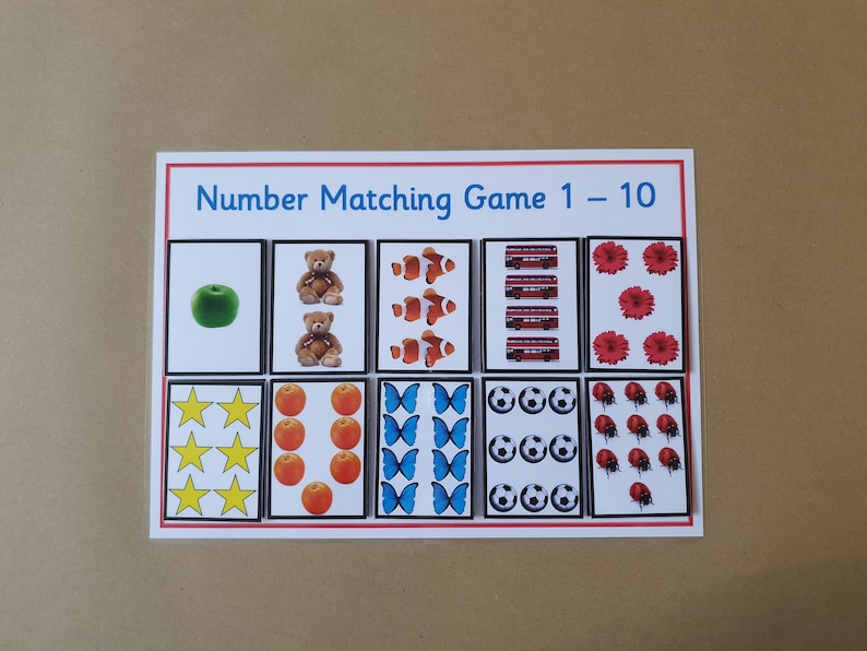 May include: A number matching game card with the title "Number Matching Game 1 - 10". The card features illustrations of various objects, including an apple, teddy bears, clownfish, buses, flowers, stars, oranges, butterflies, soccer balls, and ladybugs.