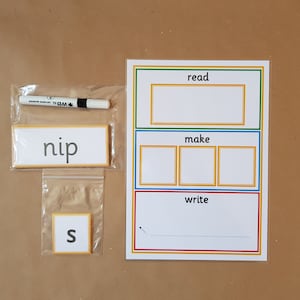 May include: Educational resources including a white marker, word cards, and a learning board. The word cards show the words "nip" and "s". The learning board has sections labelled "read", "make", and "write".