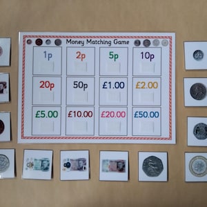 May include: A money matching game with a white board featuring slots for coins and bills, labeled with values from 1p to £50. The game includes matching currency cards, promoting financial literacy.