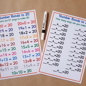 May include: Two white educational charts with orange borders and the text "Number Bonds to 20". One chart lists addition equations that equal 20. The other chart has blank equations. A white dry-erase marker is also present.
