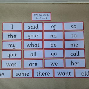 May include: Flashcards with red borders and white centres, each displaying a common sight word. The cards are arranged in a grid, with the words "RWI Red Words Sets 1 and 2" at the top. Educational resource.