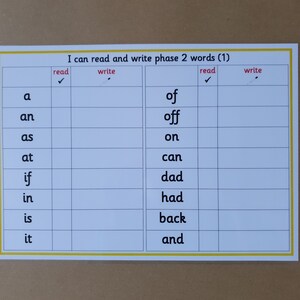 May include: A laminated educational chart with the text "I can read and write phase 2 words (1)". The chart is divided into columns for reading and writing, featuring common words like "a", "an", "as", and "of".