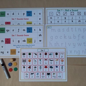May include: A set of educational games for learning sounds, with white cards displaying letters, words, and pictures. Includes dice, a marker, and coloured game pieces. Designed for early childhood education.