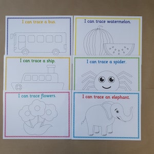 May include: Six tracing cards with colourful borders. Each card features a dotted outline of an object, including a bus, watermelon, ship, spider, flowers, and an elephant. Text on each card reads "I can trace..." followed by the object's name.