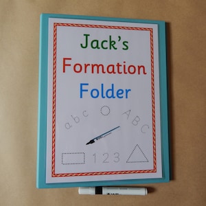 May include: A light blue folder featuring a white insert with the text Jack's Formation Folder in green, red, and blue. The insert includes dotted outlines of letters a, b, c, A, B, C, a rectangle, a triangle, and numbers 1, 2, 3, with a dry erase marker.