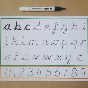 May include: A white and green alphabet and number tracing worksheet with dotted letters and numbers. A black and white marker is above the worksheet. The worksheet includes lowercase letters a-z and numbers 0-9.