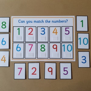 May include: A number matching game with a white background. The game features a board with the text "Can you match the numbers?" and numbers 1-10. Individual number cards are scattered around the board. The numbers are in various colours.