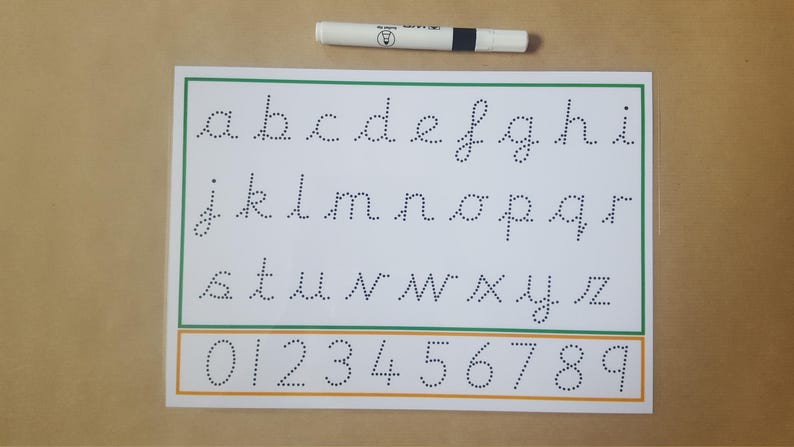 May include: A white paper with the alphabet and numbers in dotted lines for tracing, with a green and orange border. A white and black pen is at the top. Educational material for learning to write.