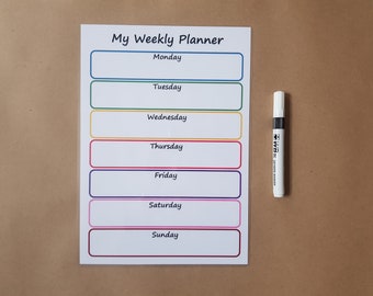 May include: A white weekly planner sheet with the text My Weekly Planner at the top, featuring seven horizontal rectangular boxes with colored borders for each day of the week, accompanied by a white dry-erase marker with a black cap.