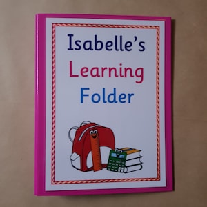 May include: A pink-framed learning folder with the text "Isabelle's Learning Folder" in pink and blue. The folder features a red backpack, a ruler, and a stack of books with a calculator illustration.