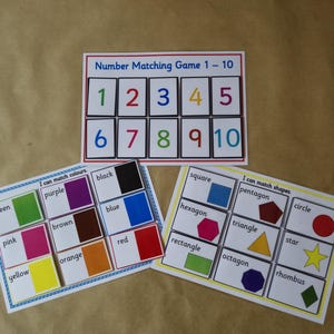 May include: A set of educational matching games. The top card is a number matching game from 1 to 10. The other two cards are for matching colours and shapes. The cards have a white background with colourful text and shapes.