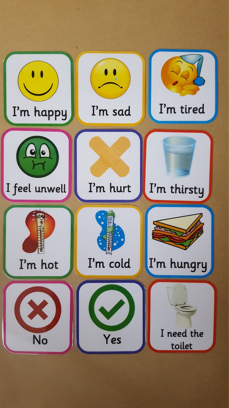 May include: A set of twelve square cards with rounded corners, each featuring a different emotion or need. The cards display images of a smiley face, a sad face, a sleeping face, a bandage, a glass of water, a sandwich, a thermometer, and a toilet. Text accompanies each image.