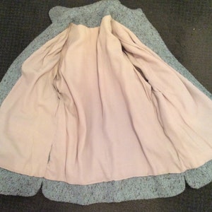 May include: A teal blue knitted jacket with a light pink lining. The jacket has a label that reads "Made in China".