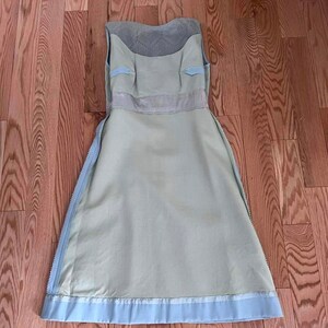 May include: A light blue sleeveless dress with a white lace bodice and a light green skirt. The dress has a zipper on each side and a white ribbon around the waist.