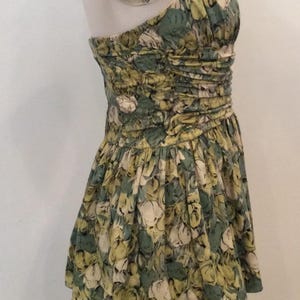 May include: A green and yellow floral print halter dress with a gathered bodice and a short skirt.