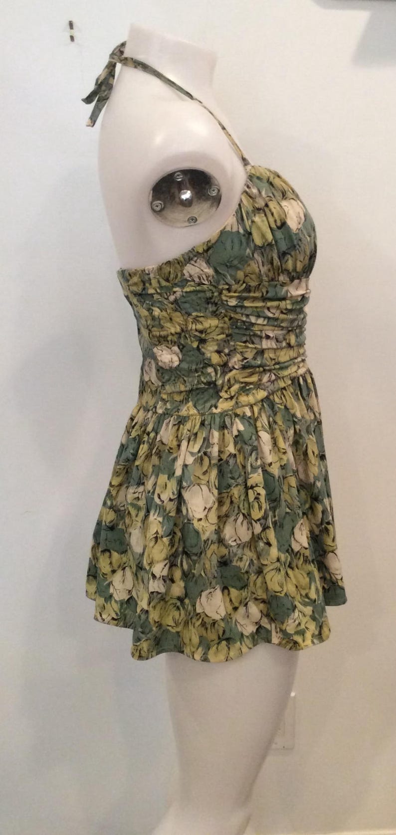 May include: A green and yellow floral print halter dress with a gathered bodice and a short skirt.