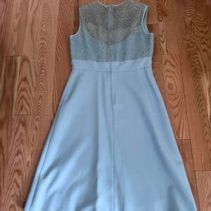 May include: A light blue sleeveless dress with a lace bodice. The dress has a fitted bodice and a flowing skirt.