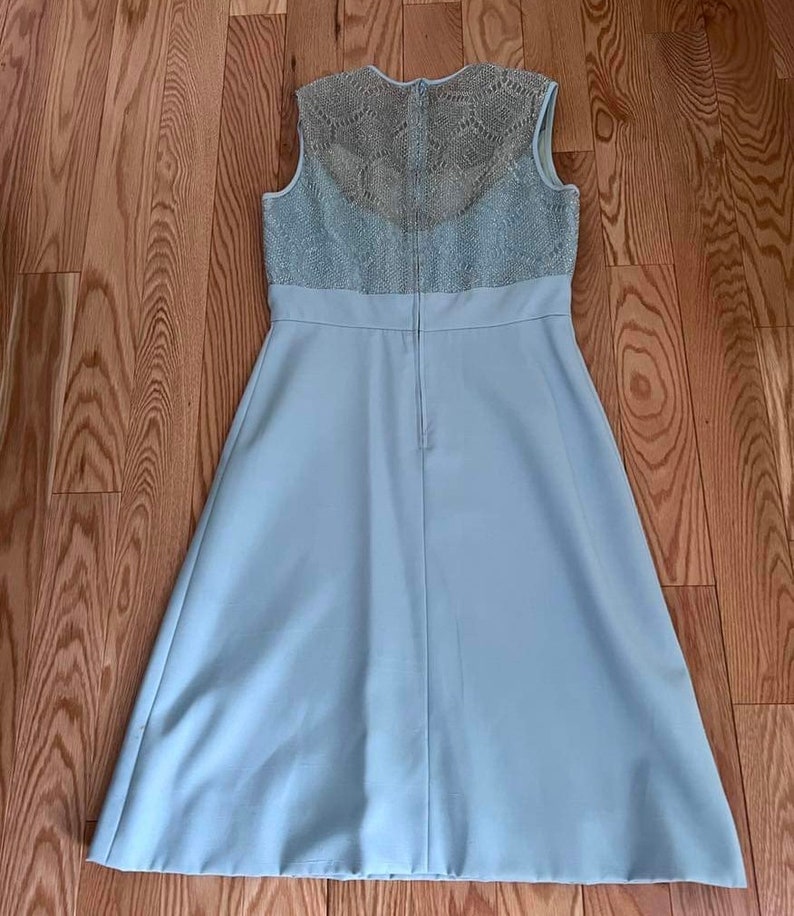 May include: A light blue sleeveless dress with a lace bodice. The dress has a fitted bodice and a flowing skirt.