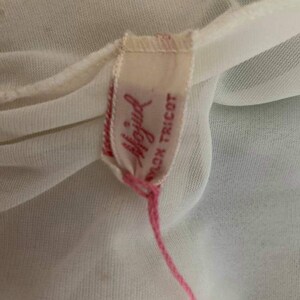 May include: A white nylon tricot fabric label with pink stitching. The label has the text "Playful" in pink lettering and "Nylon Tricot" in black lettering.