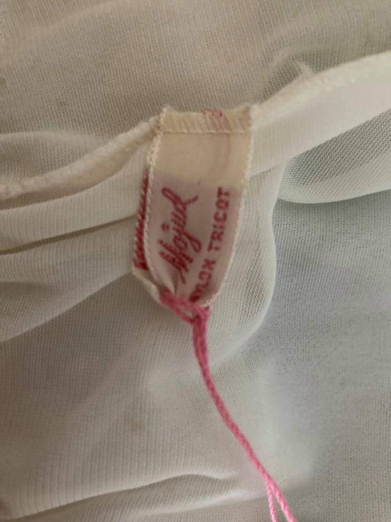 May include: A white nylon tricot fabric label with pink stitching. The label has the text "Playful" in pink lettering and "Nylon Tricot" in black lettering.