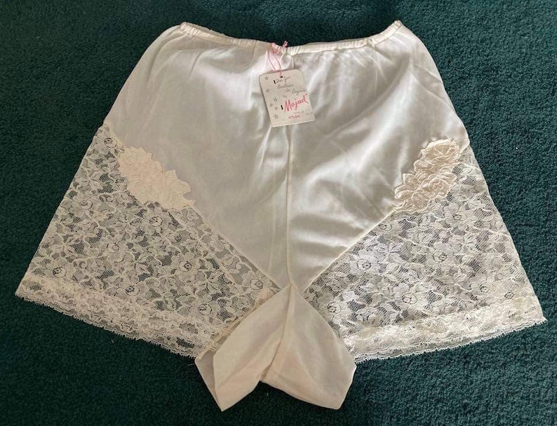 May include: White lace trimmed nylon underwear with a pink label that says "Magical" on it.