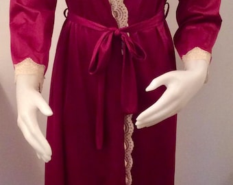 May include: A long, burgundy robe with a lace trim around the neckline and down the front. The robe has a tie belt and long sleeves.
