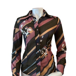 May include: A long-sleeved button-down shirt with a colorful diagonal striped pattern in shades of brown, pink, orange, and blue. The shirt features a repeating illustration of a woman in a hat. The shirt is displayed on a white mannequin.