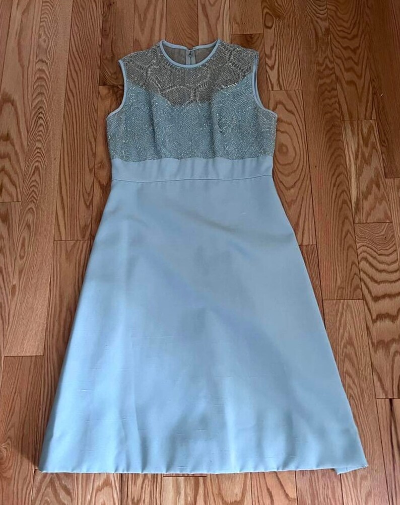 May include: A light blue sleeveless dress with a lace bodice. The dress has a fitted bodice and a full skirt.