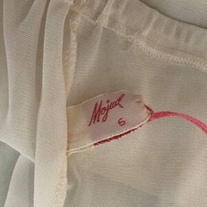 May include: A white sheer fabric with a pink label that says "Mojud" and a size 6.