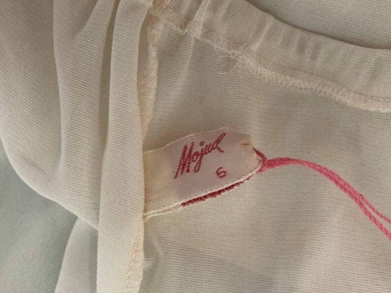 May include: A white sheer fabric with a pink label that says "Mojud" and a size 6.