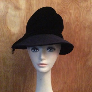 May include: A black velvet hat with a wide brim and a slight upward curve on the crown.