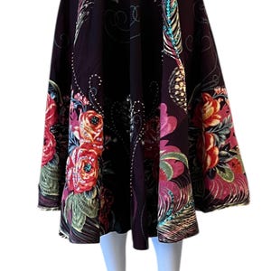 May include: A dark burgundy skirt with a floral pattern featuring red, pink, and yellow roses. The skirt has a full, flowing shape and is decorated with sequins and other embellishments.