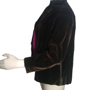 May include: A brown velvet jacket with a black lace collar. The jacket has a long sleeve and a fitted silhouette.