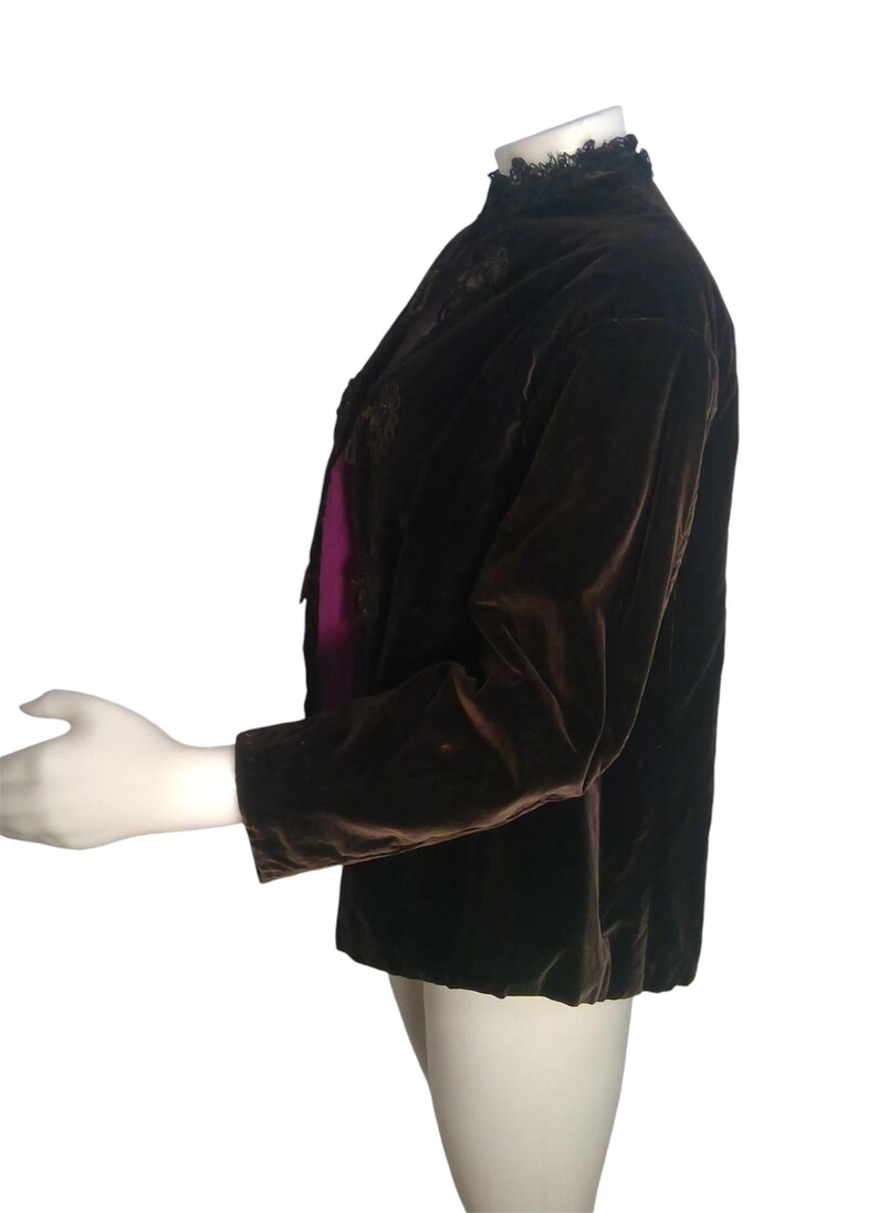 May include: A brown velvet jacket with a black lace collar. The jacket has a long sleeve and a fitted silhouette.