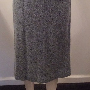 May include: A gray tweed skirt with a straight silhouette. The skirt is knee-length and has a simple design.
