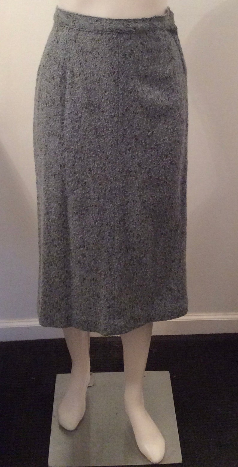 May include: A gray tweed skirt with a straight silhouette. The skirt is knee-length and has a simple design.