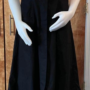 May include: A black dress with a v-neck and short sleeves. The dress has a button-up front and a flared skirt.