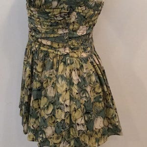 May include: A green and yellow floral print halter-style swimsuit with a gathered bodice and a full skirt.