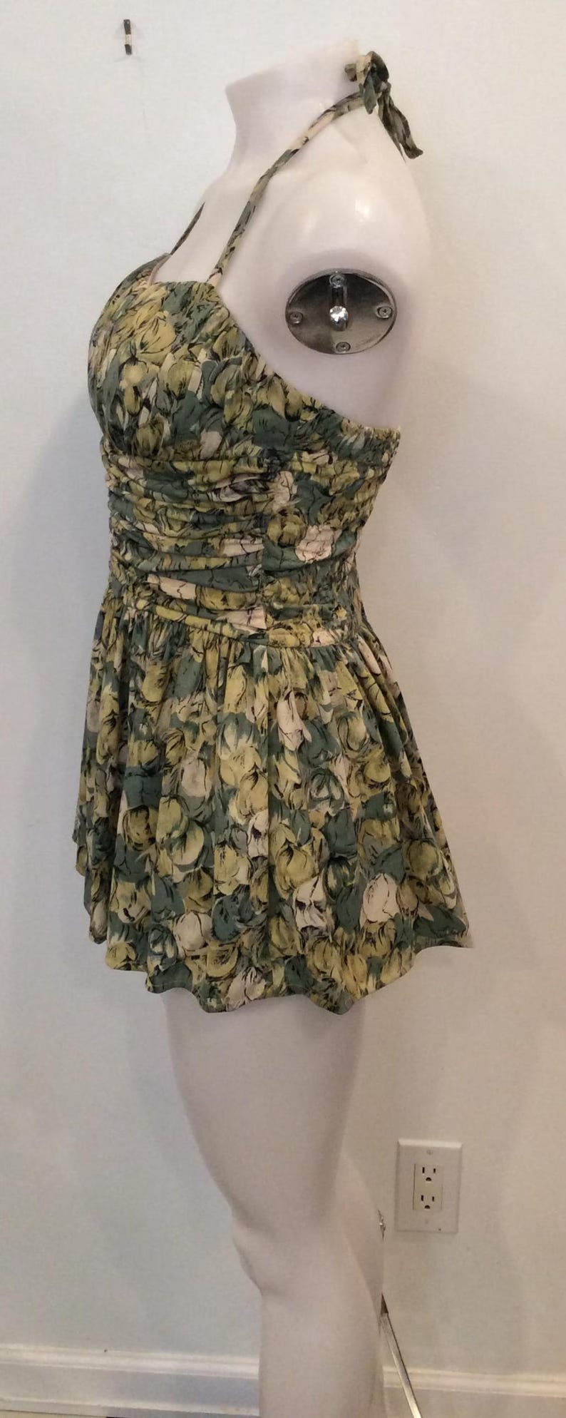 May include: A green and yellow floral print halter-style swimsuit with a gathered bodice and a full skirt.