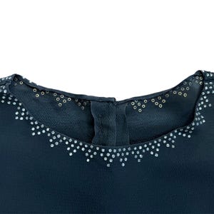 May include: A dark blue top with a decorative neckline featuring a row of silver rhinestones.