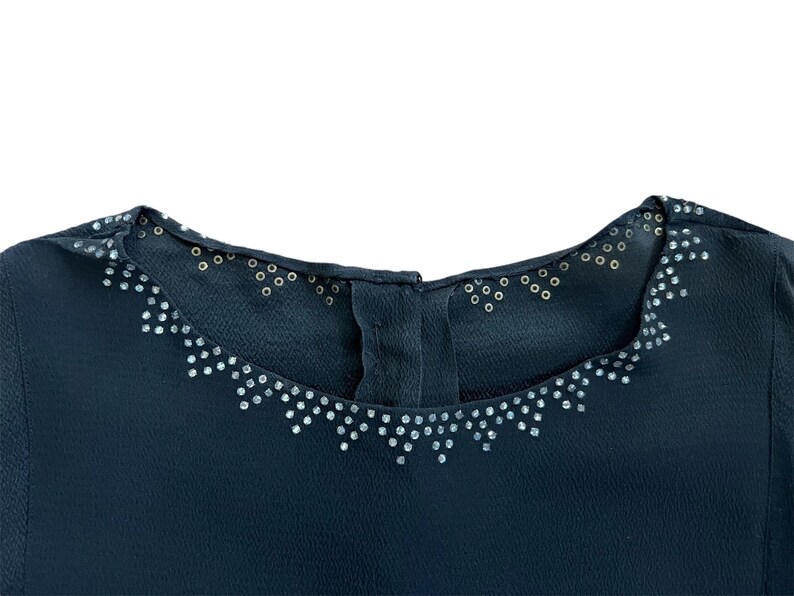 May include: A dark blue top with a decorative neckline featuring a row of silver rhinestones.