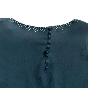 May include: A black dress with a row of buttons down the back and a sparkly trim around the neckline.