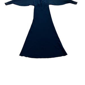 May include: A long, dark blue dress with a beaded neckline and long sleeves. The dress has a fitted bodice and a flowing skirt.