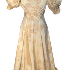 May include: A white dress with a floral pattern and puffed sleeves. The dress has a fitted bodice and a flowing skirt.