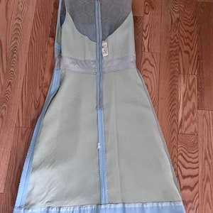 May include: A light blue sleeveless dress with a lace overlay and a zipper down the back. The dress has a light blue trim at the bottom.