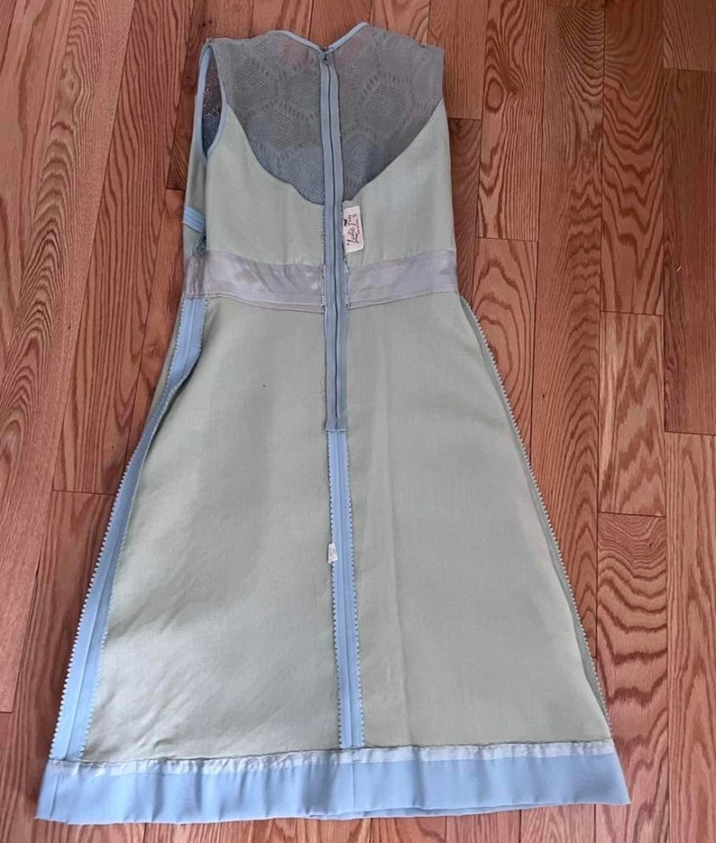 May include: A light blue sleeveless dress with a lace overlay and a zipper down the back. The dress has a light blue trim at the bottom.