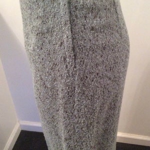 May include: A gray skirt with a zipper closure and a button at the top. The skirt is made of a textured fabric.