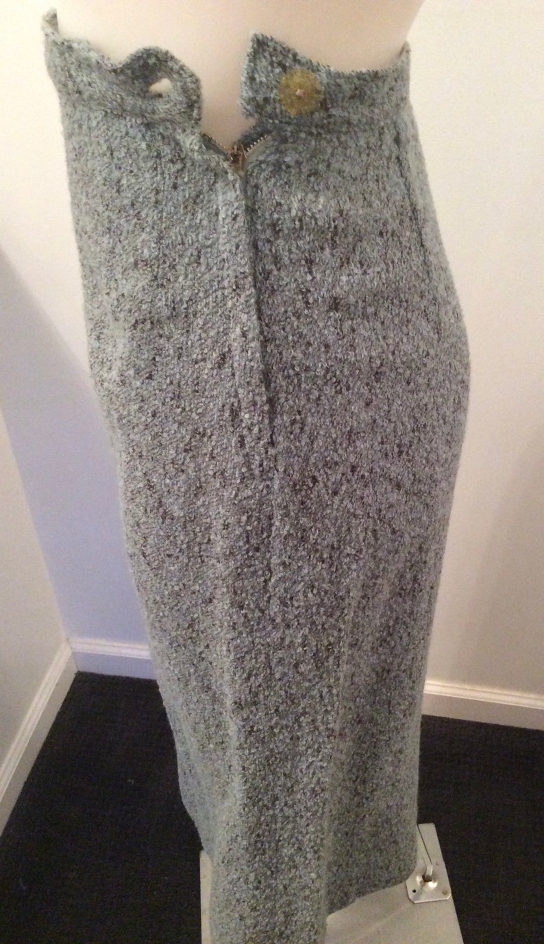 May include: A gray skirt with a zipper closure and a button at the top. The skirt is made of a textured fabric.